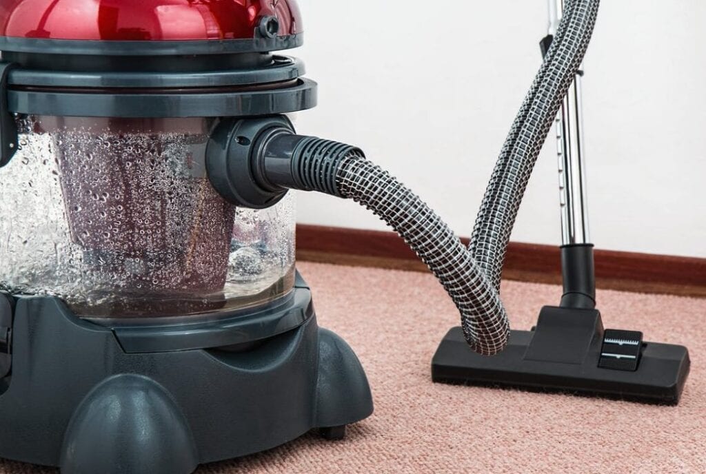 black and red canister vacuum cleaner on floor · f