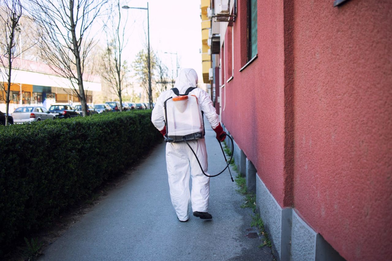 worker chemical protection suit spraying disinfectant public surfaces